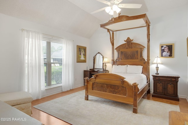 bedroom with ceiling fan, lofted ceiling, and light wood-type flooring