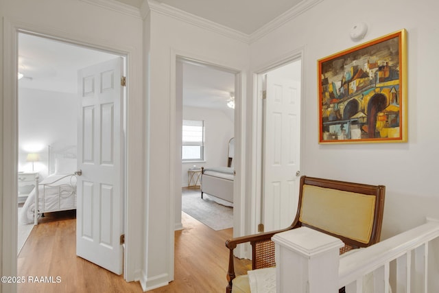 hallway with light wood-type flooring and crown molding