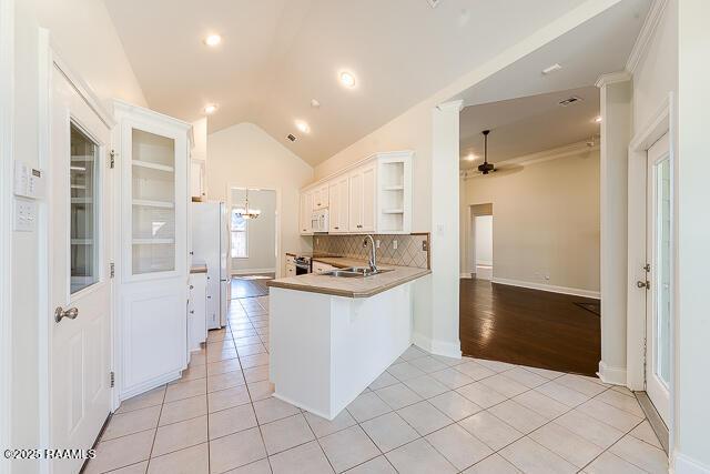 kitchen featuring white appliances, white cabinets, sink, kitchen peninsula, and light tile patterned floors