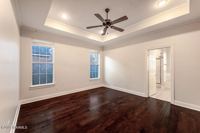 empty room with ceiling fan, light wood-type flooring, a tray ceiling, and crown molding