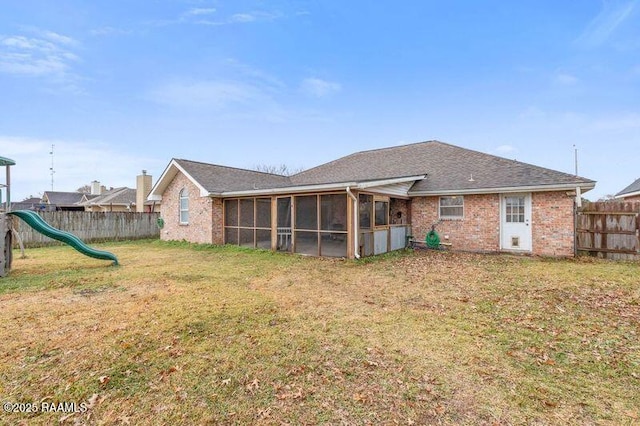 back of property with a yard, a sunroom, and a playground