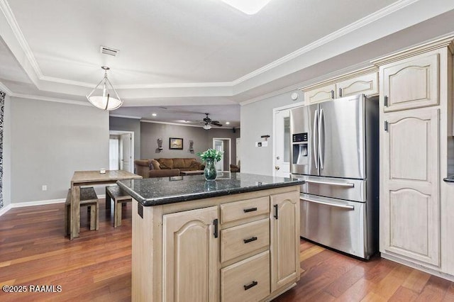 kitchen featuring dark wood-type flooring, dark stone countertops, a tray ceiling, stainless steel fridge, and a kitchen island