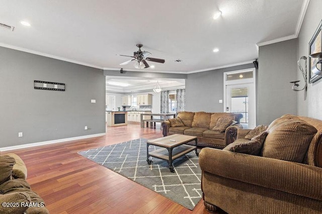 living room featuring crown molding, wood-type flooring, and ceiling fan