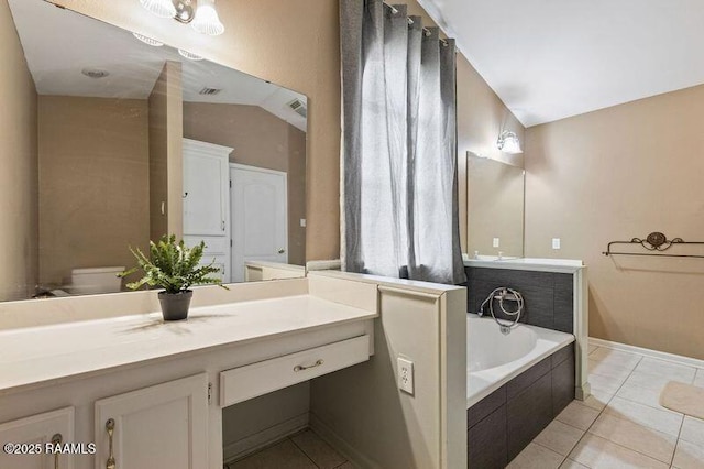 bathroom featuring tile patterned flooring, lofted ceiling, tiled tub, and toilet