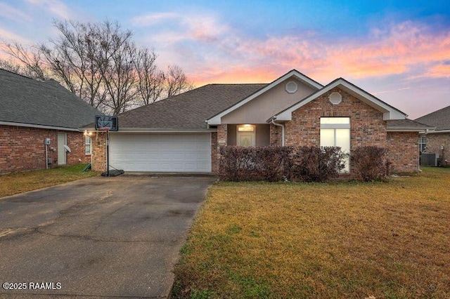 view of front of property with a garage, a yard, and cooling unit