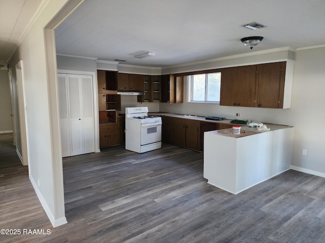 kitchen featuring gas range gas stove, dark wood-type flooring, kitchen peninsula, crown molding, and dark brown cabinets