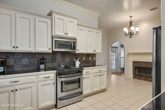 kitchen featuring decorative light fixtures, decorative backsplash, stainless steel appliances, ornamental molding, and light tile patterned floors