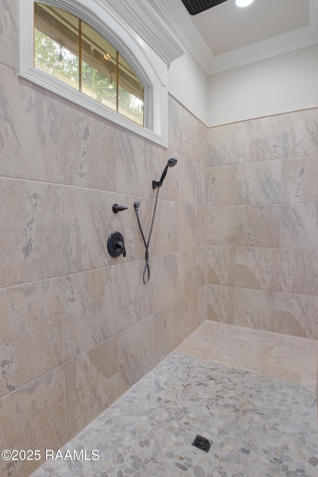 bathroom featuring a wealth of natural light, ornamental molding, and a tile shower