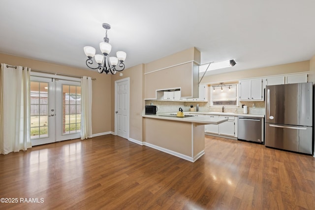 kitchen featuring appliances with stainless steel finishes, decorative light fixtures, white cabinetry, backsplash, and kitchen peninsula