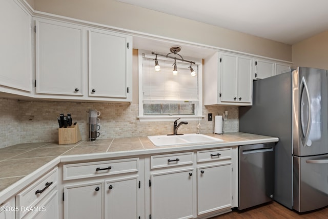 kitchen featuring sink, stainless steel appliances, white cabinetry, and decorative backsplash