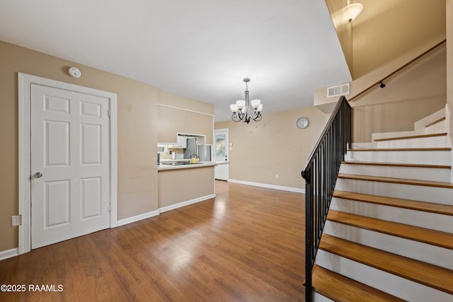 staircase featuring hardwood / wood-style flooring and an inviting chandelier