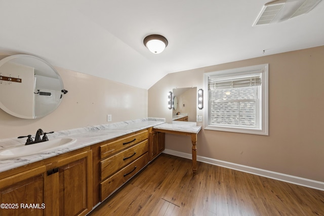 bathroom with wood-type flooring, lofted ceiling, and vanity