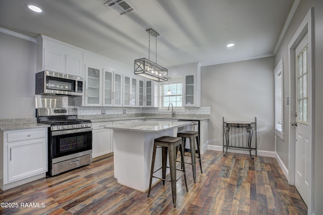 kitchen featuring light stone countertops, a center island, white cabinets, and appliances with stainless steel finishes