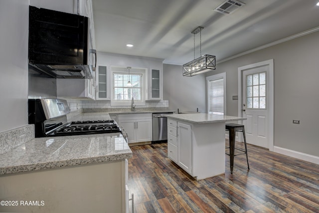 kitchen featuring decorative light fixtures, white cabinetry, sink, a center island, and stainless steel appliances