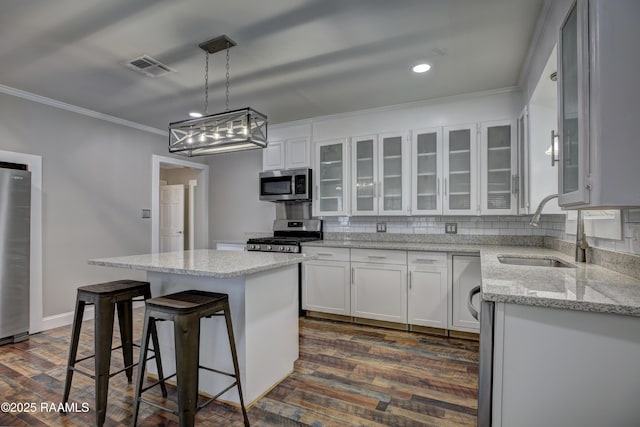 kitchen featuring sink, white cabinetry, decorative light fixtures, a center island, and stainless steel appliances