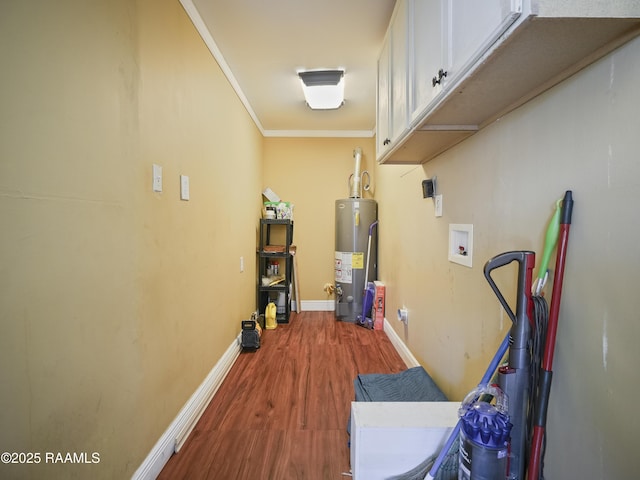 laundry room featuring gas water heater, hardwood / wood-style floors, cabinets, ornamental molding, and washer hookup