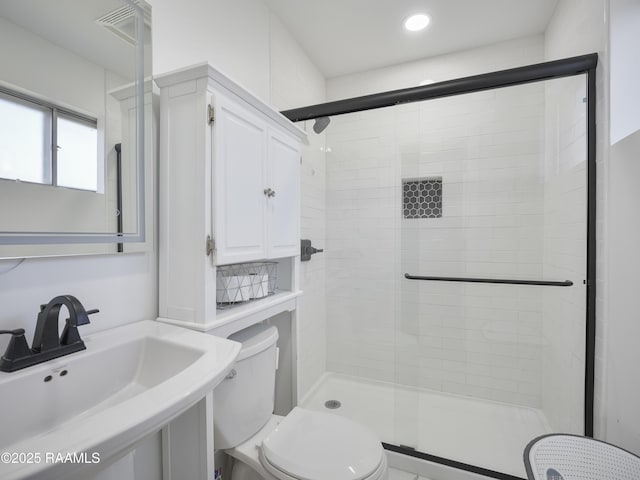 bathroom with sink, toilet, and a shower with door