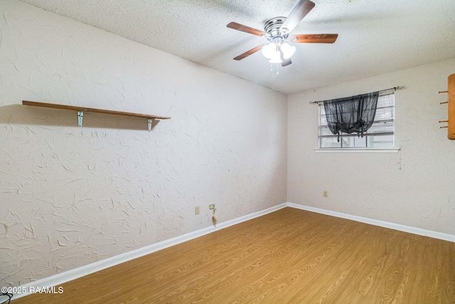 empty room with ceiling fan, wood-type flooring, and a textured ceiling