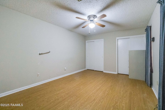 unfurnished bedroom with multiple closets, ceiling fan, a textured ceiling, and light wood-type flooring