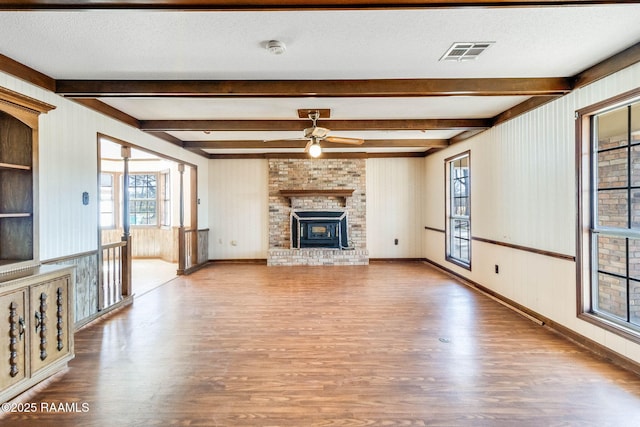 unfurnished living room featuring visible vents, a textured ceiling, and wood finished floors