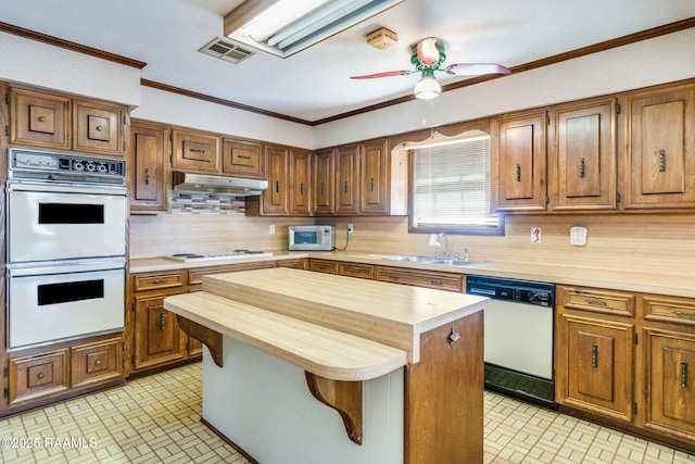 kitchen featuring white appliances, visible vents, a sink, under cabinet range hood, and wood counters