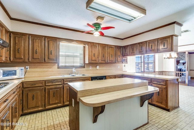 kitchen featuring a peninsula, white microwave, a wealth of natural light, and a sink