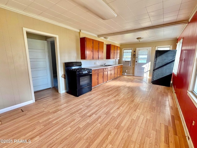 kitchen with sink, crown molding, light wood-type flooring, black range with gas stovetop, and cooling unit