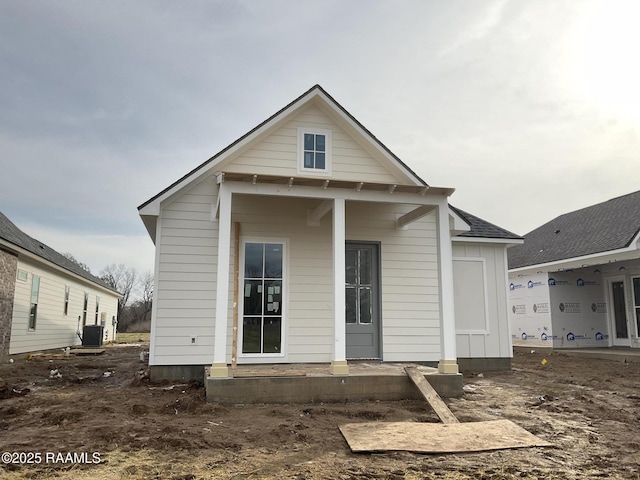 rear view of property with board and batten siding, roof with shingles, and cooling unit