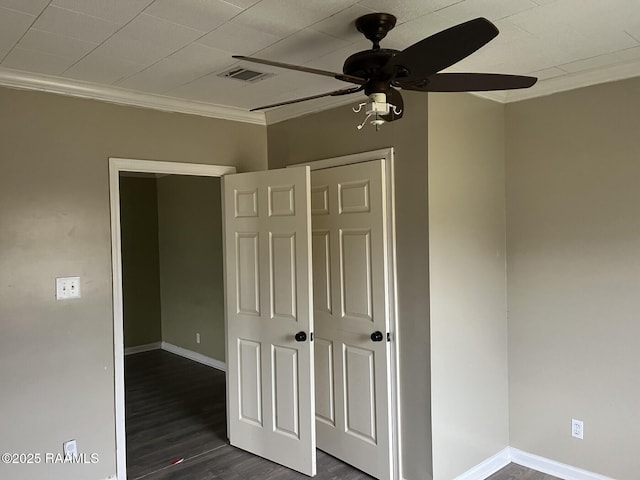 unfurnished bedroom with dark hardwood / wood-style flooring, crown molding, ceiling fan, and a closet