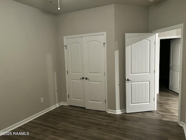 unfurnished bedroom with dark wood-type flooring and a closet