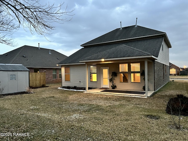 rear view of property with a patio area, a shed, and a lawn