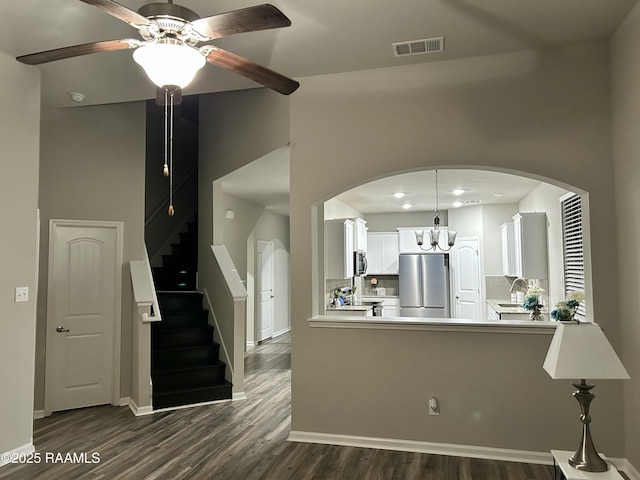 kitchen featuring appliances with stainless steel finishes, white cabinetry, dark hardwood / wood-style flooring, decorative light fixtures, and kitchen peninsula