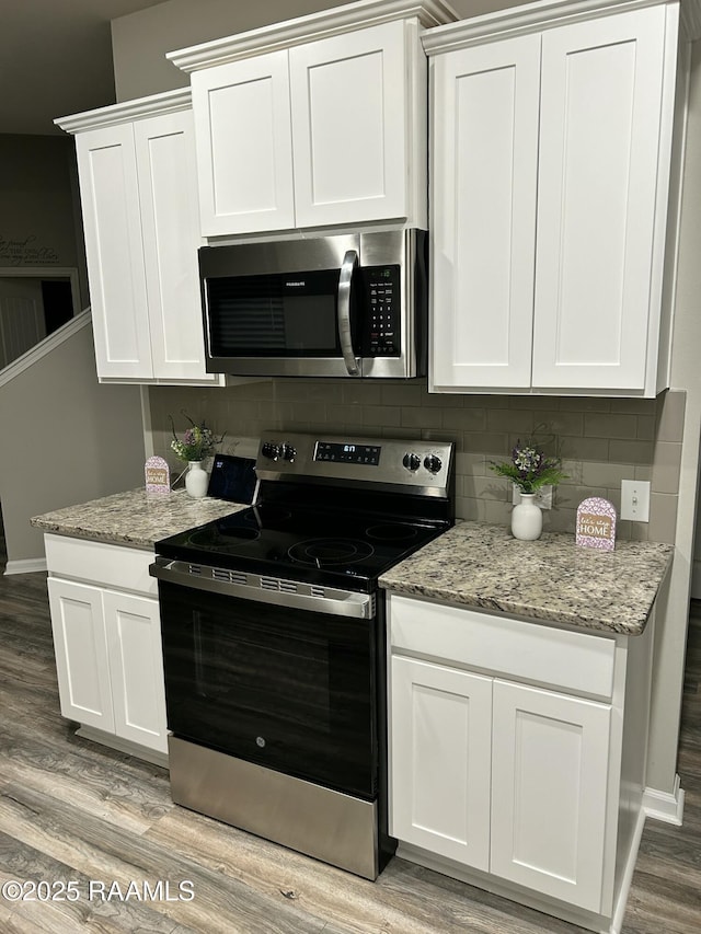 kitchen featuring tasteful backsplash, white cabinets, light stone counters, light hardwood / wood-style floors, and stainless steel appliances