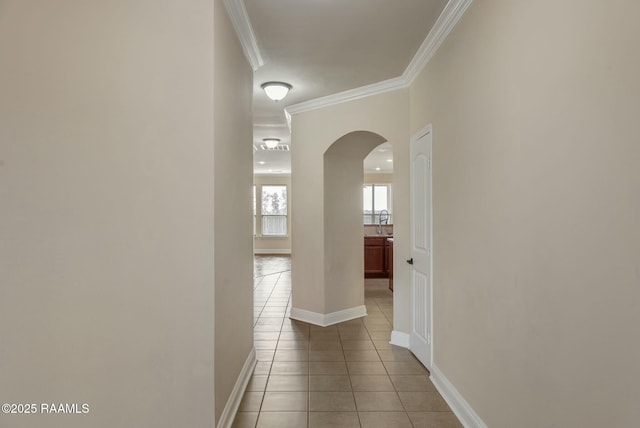 corridor with light tile patterned flooring, sink, and crown molding