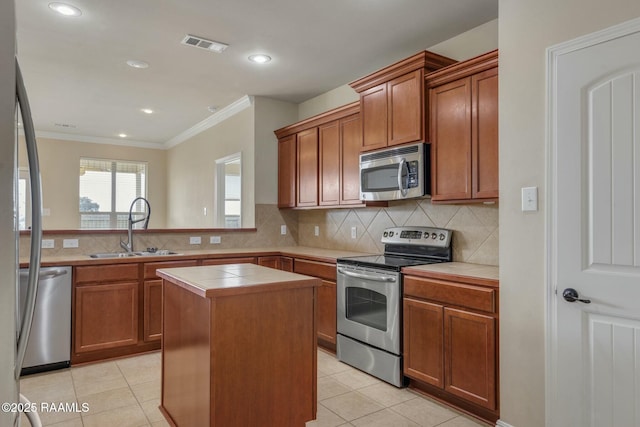 kitchen featuring light tile patterned flooring, a kitchen island, appliances with stainless steel finishes, sink, and tile counters