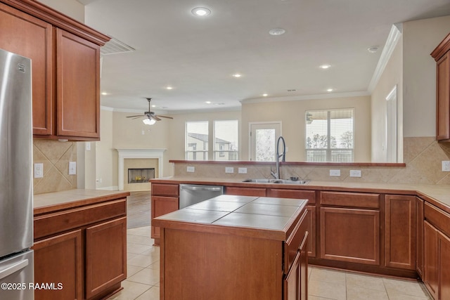 kitchen featuring sink, light tile patterned floors, tile counters, a kitchen island, and stainless steel appliances