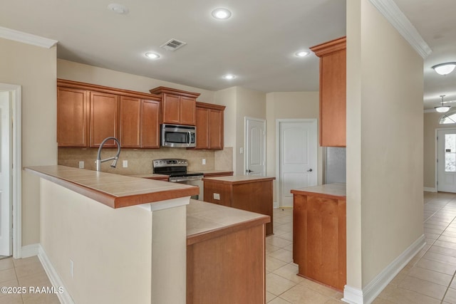 kitchen with light tile patterned flooring, crown molding, kitchen peninsula, stainless steel appliances, and decorative backsplash