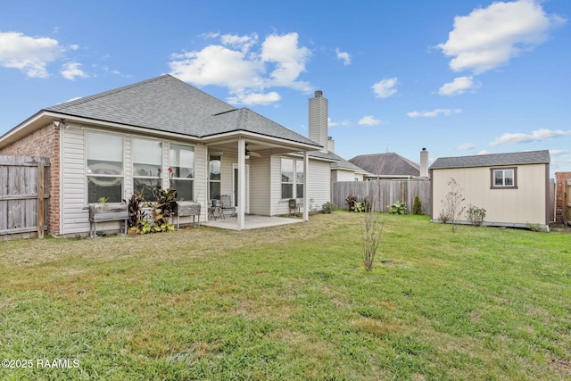 back of property featuring a storage unit, a lawn, ceiling fan, and a patio area