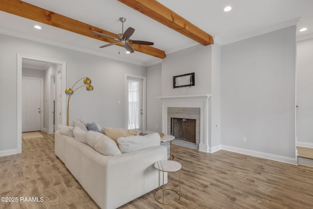 living room with beam ceiling, ornamental molding, light wood-type flooring, and a high end fireplace