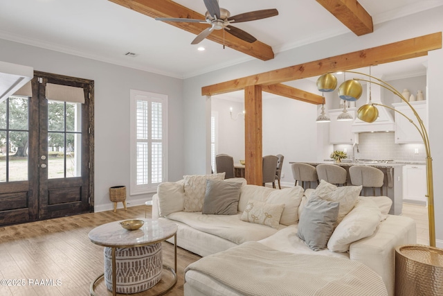 living room with ornamental molding, sink, ceiling fan with notable chandelier, and light hardwood / wood-style floors