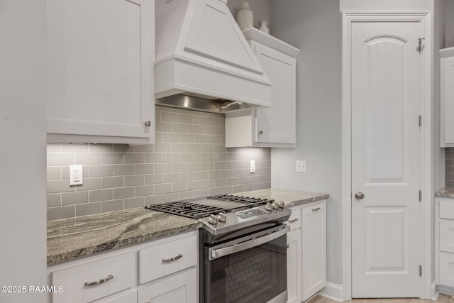 kitchen with white cabinets, backsplash, gas stove, light stone countertops, and custom range hood