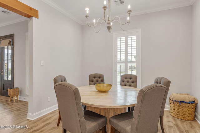 dining area featuring crown molding, an inviting chandelier, and light hardwood / wood-style floors