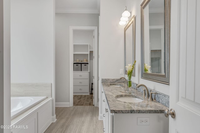 bathroom featuring vanity, a tub to relax in, crown molding, and hardwood / wood-style flooring