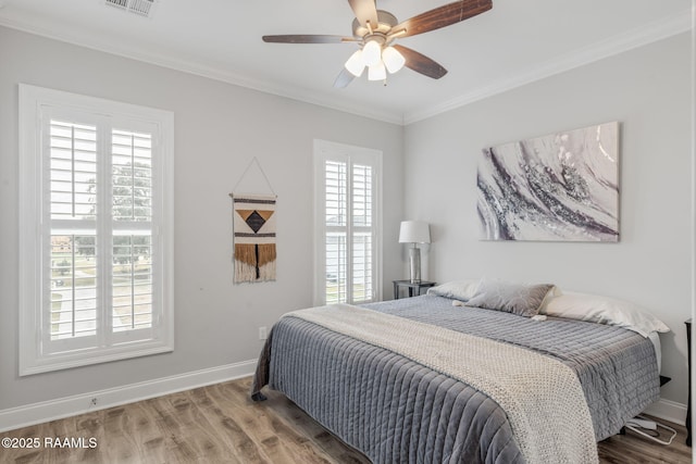 bedroom featuring hardwood / wood-style floors, ornamental molding, and ceiling fan