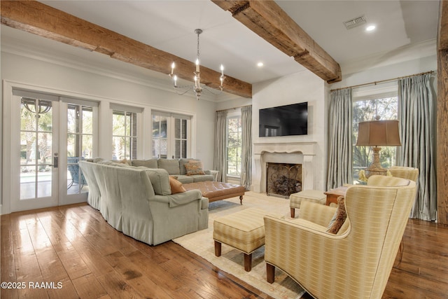 living room featuring french doors, a wealth of natural light, beam ceiling, and wood-type flooring