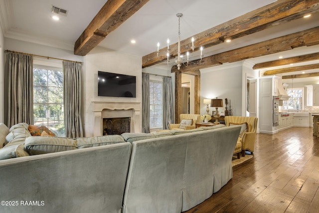 living room featuring an inviting chandelier, beam ceiling, and dark hardwood / wood-style flooring