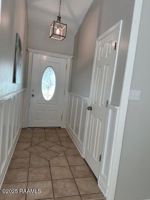 entryway with a textured ceiling and light tile patterned floors