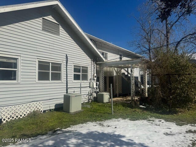 view of snow covered exterior featuring cooling unit and a pergola