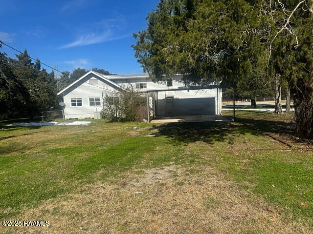 back of house with a garage and a yard