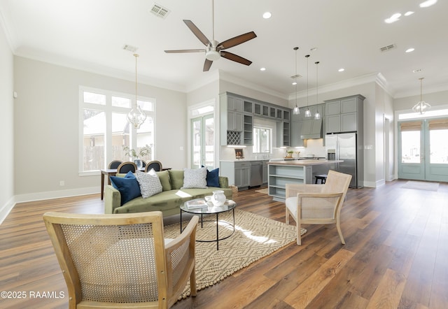 living room featuring dark hardwood / wood-style flooring, ceiling fan with notable chandelier, ornamental molding, and french doors